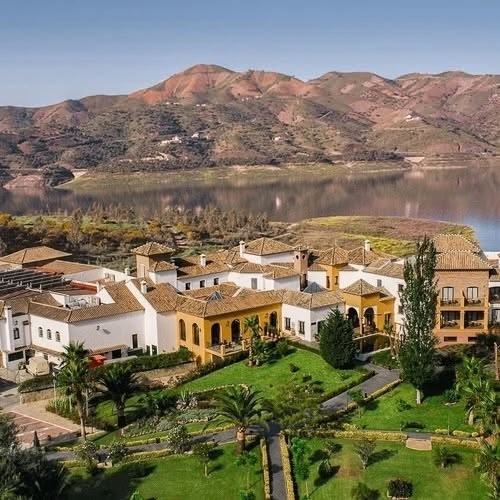 Villas de estilo mediterráneo junto a un lago, con montañas al fondo, en complejo B Bou Hotels.